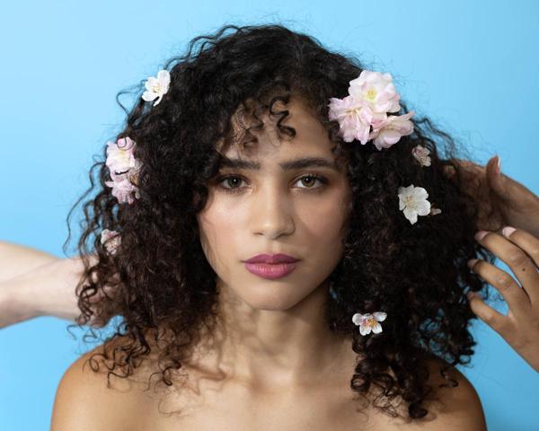Latinx female model with flowers in hair on blue backdrop photographed by Marty Gottlieb